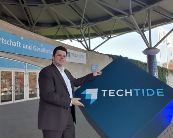 Christoph Rothe zeigt das TechTide-Schild am Eingang des Convention Centers